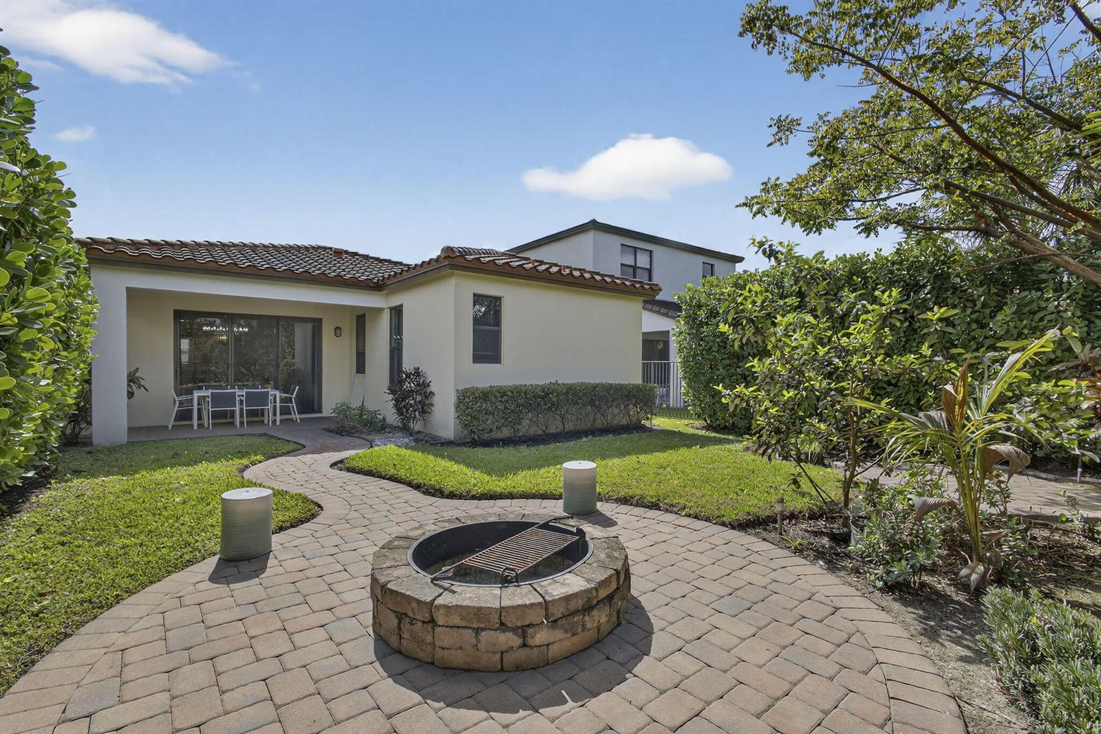 A backyard features a stone fire pit, a paved patio, and a covered dining area — 5563 Starfish Road, Westlake FL 33470, WESTLAKE, FL