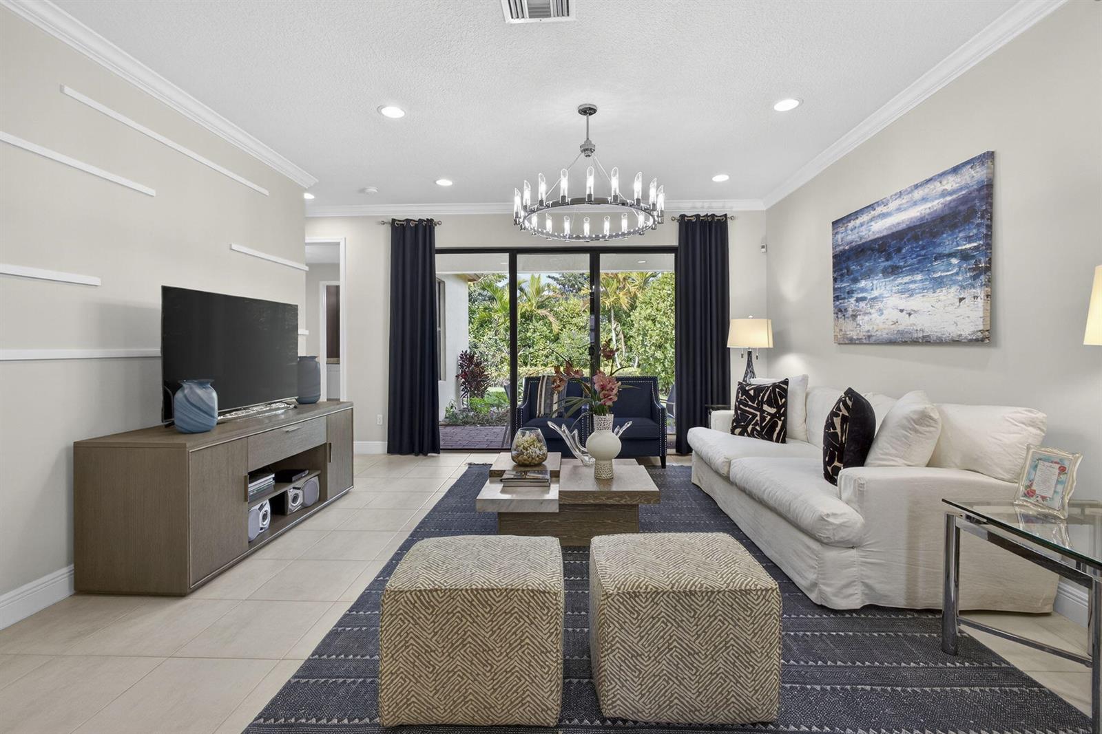 A living room features a white sofa, dark blue rug, and sliding glass doors to a patio — 5563 Starfish Road, Westlake FL 33470, WESTLAKE, FL