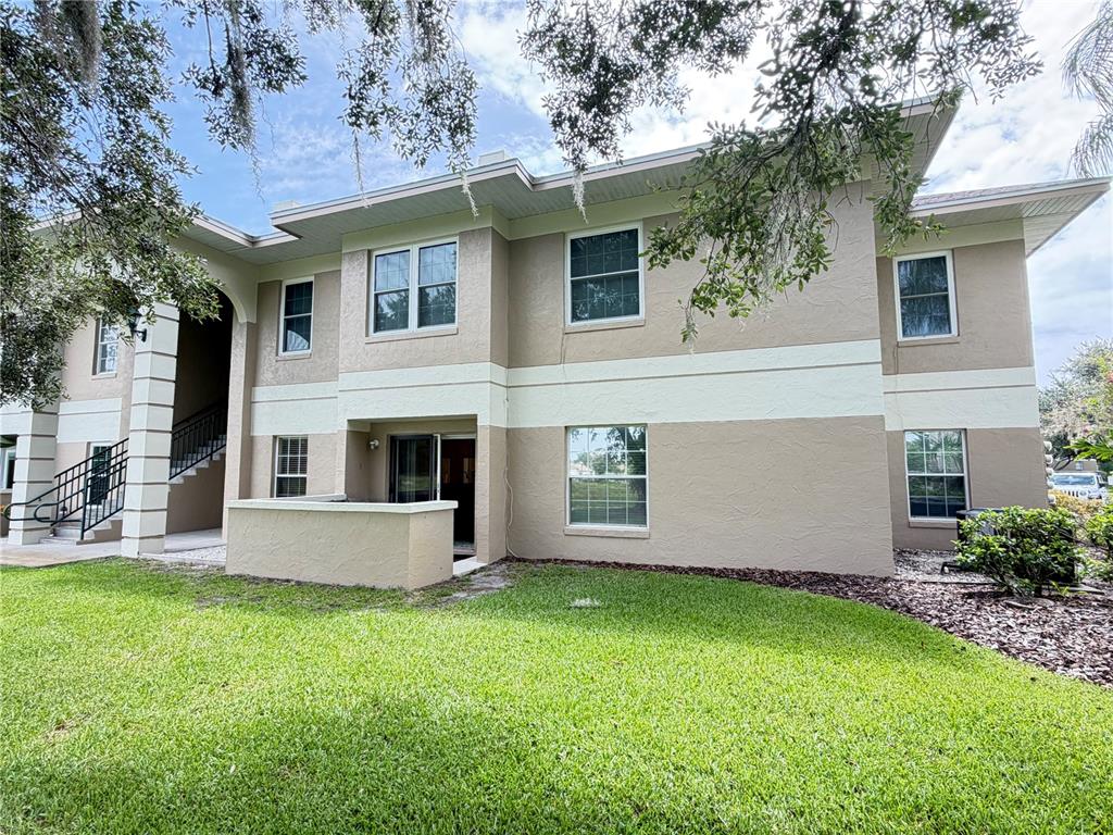 A two-story beige apartment building exterior with a ground-level patio and a staircase — 802 EAGLE POND DRIVE UNIT 802, WINTER HAVEN, FL