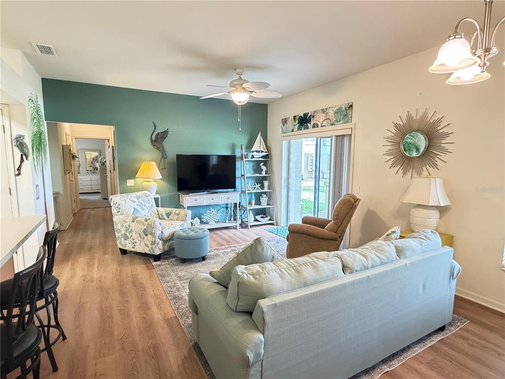A living room features a teal accent wall, light wood flooring, and coastal-themed decor — 802 EAGLE POND DRIVE UNIT 802, WINTER HAVEN, FL