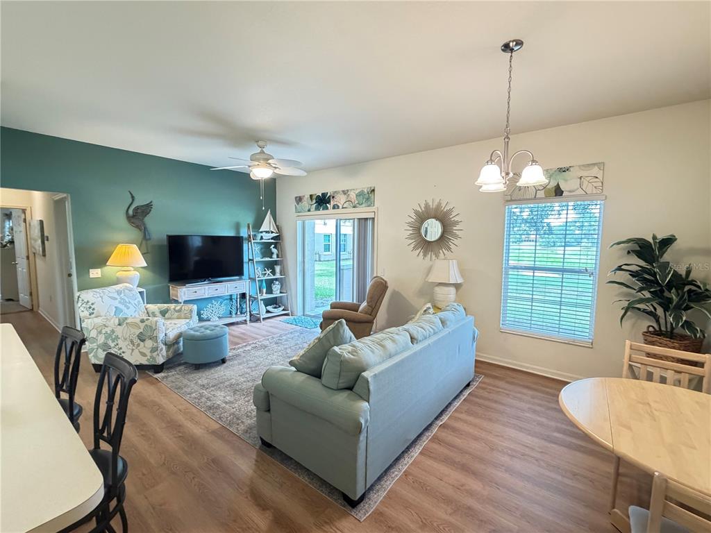 A living room features a teal accent wall, a sofa, a patterned armchair, and wood-look flooring — 802 EAGLE POND DRIVE UNIT 802, WINTER HAVEN, FL