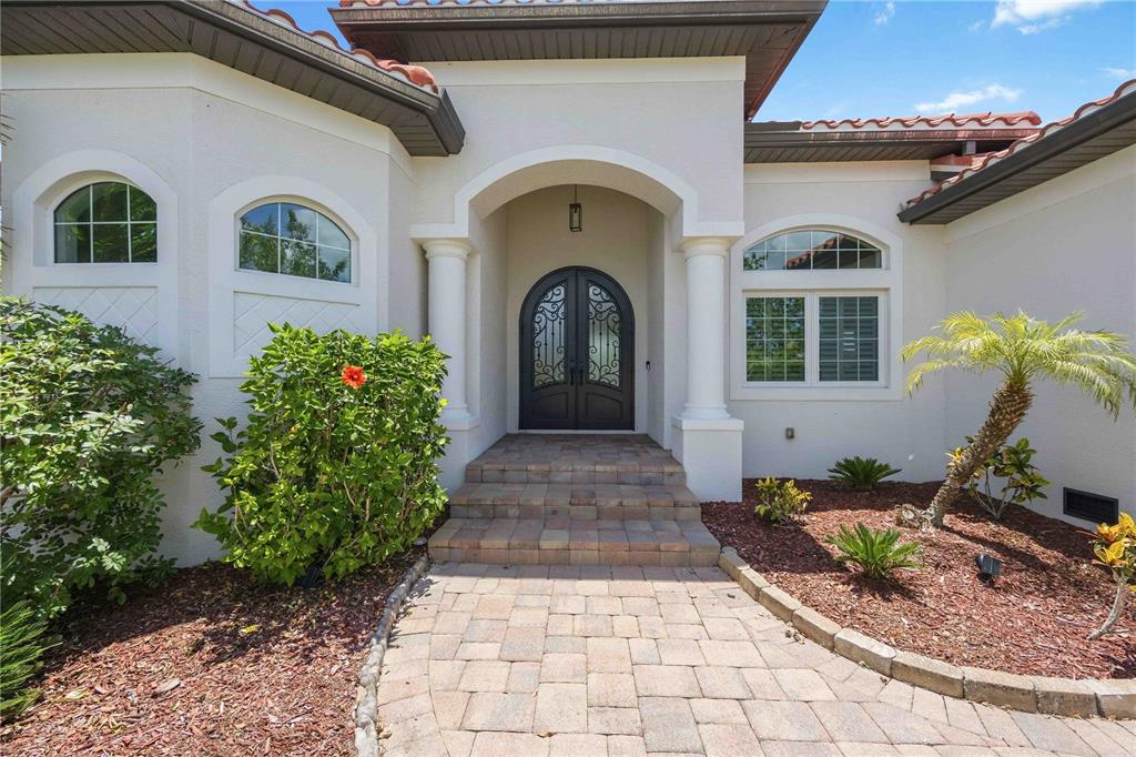 The exterior of a house features a paved walkway, arched double doors, and white columns — 10386 WINNIPEG STREET, PORT CHARLOTTE, FL