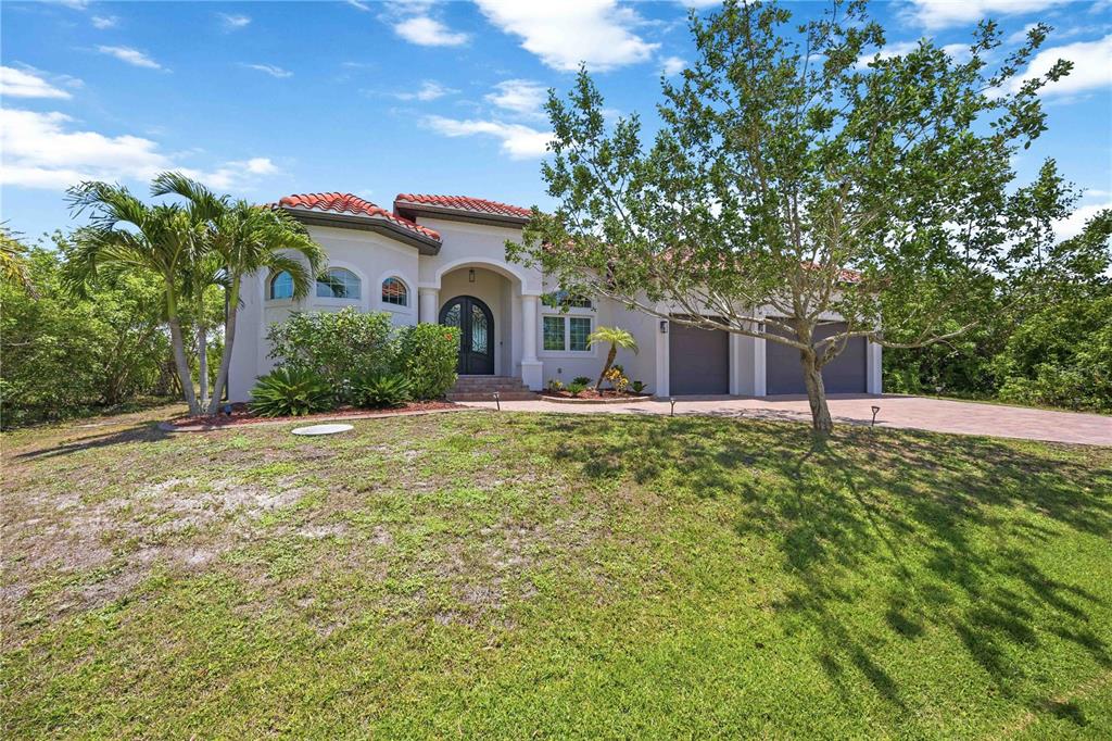 A single-story stucco house with a red tile roof and a three-car garage — 10386 WINNIPEG STREET, PORT CHARLOTTE, FL