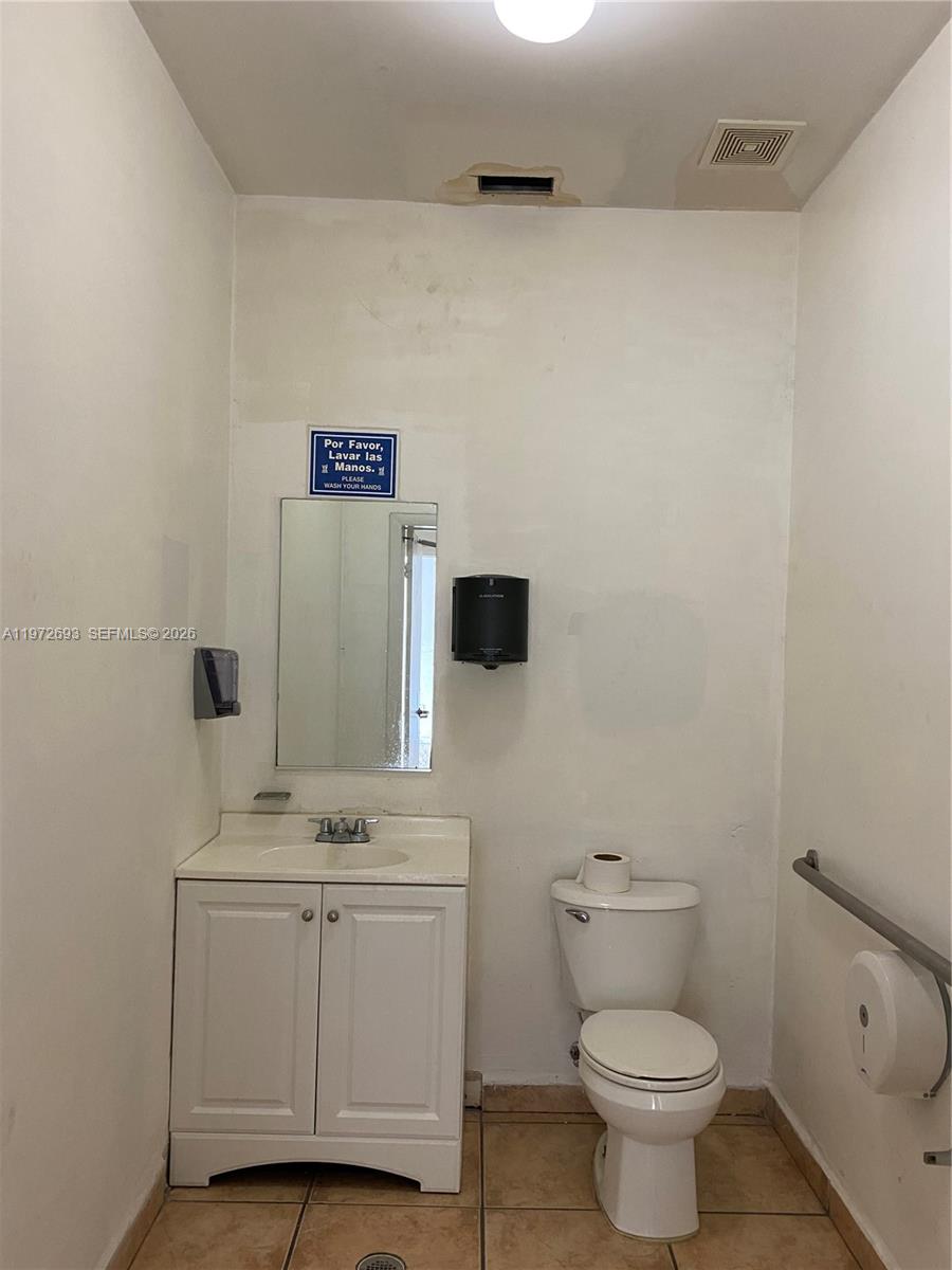 A small bathroom features a white vanity, a toilet, and a wall-mounted hand soap dispenser — 2431 W 80th St # C, Hialeah FL 33016, HIALEAH, FL