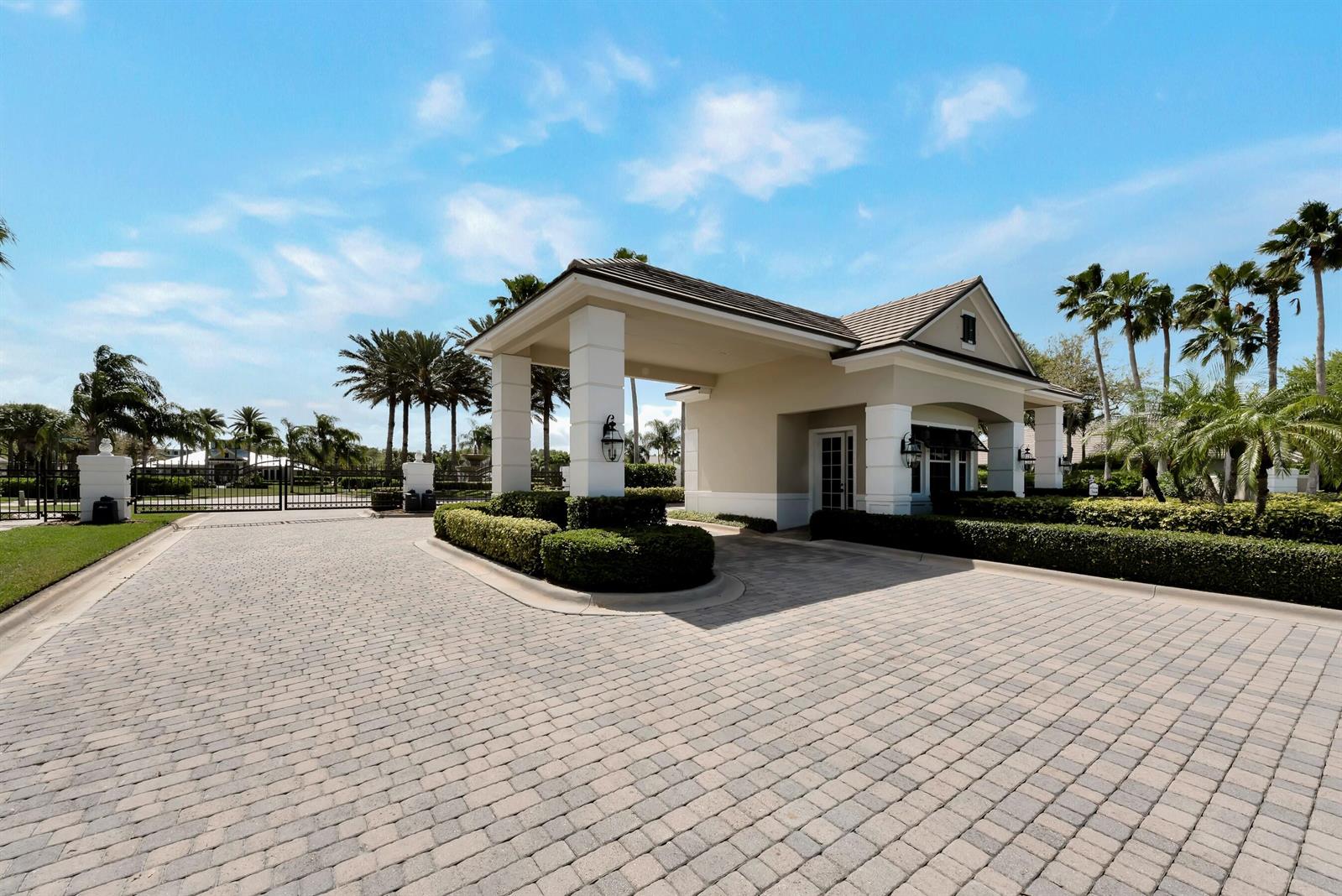 A paved driveway leads to a gated community entrance with a covered guardhouse and landscaping — VERO BEACH, FL
