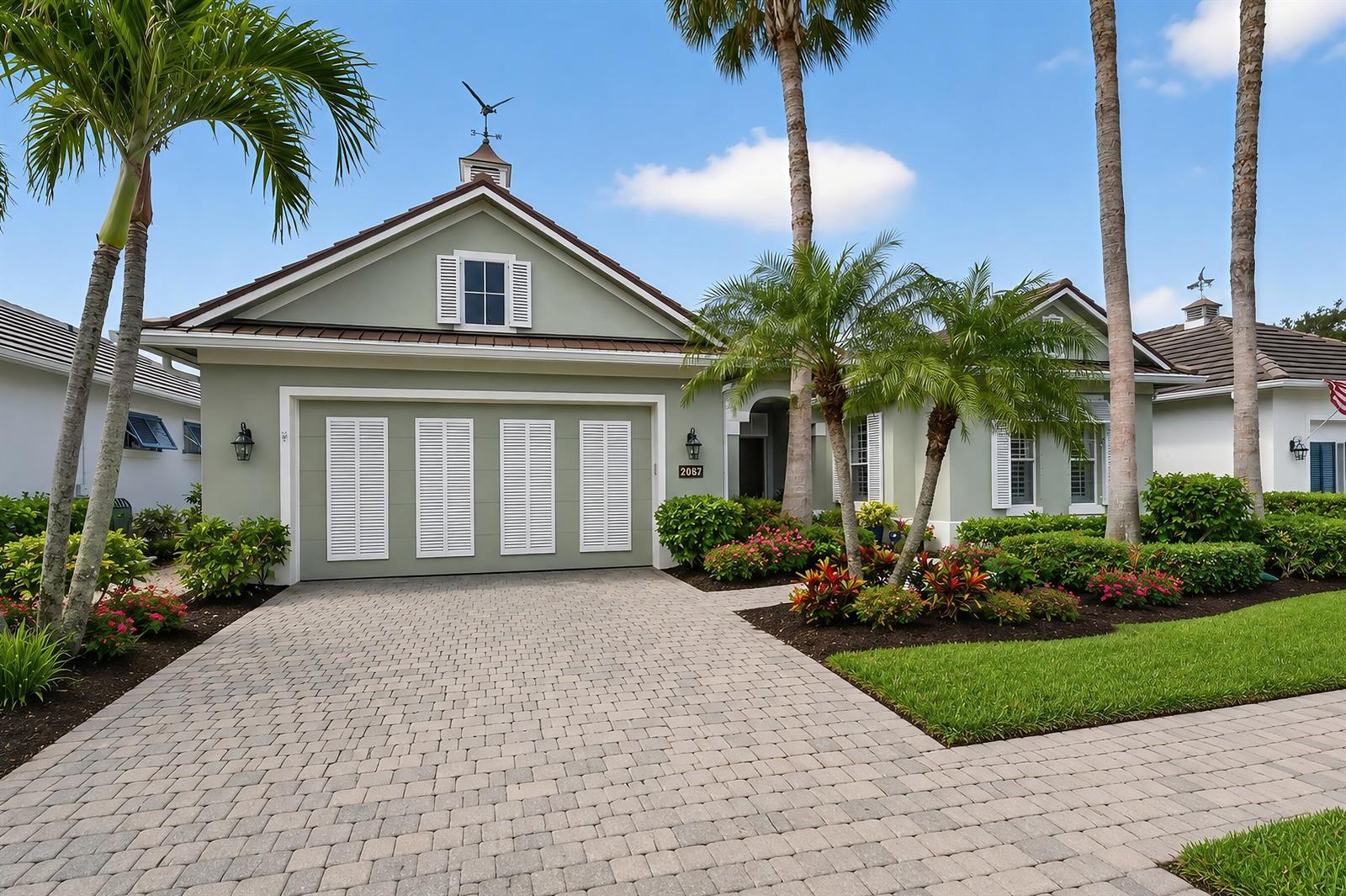 A light green house with a paved driveway, palm trees, and a cupola on top — VERO BEACH, FL