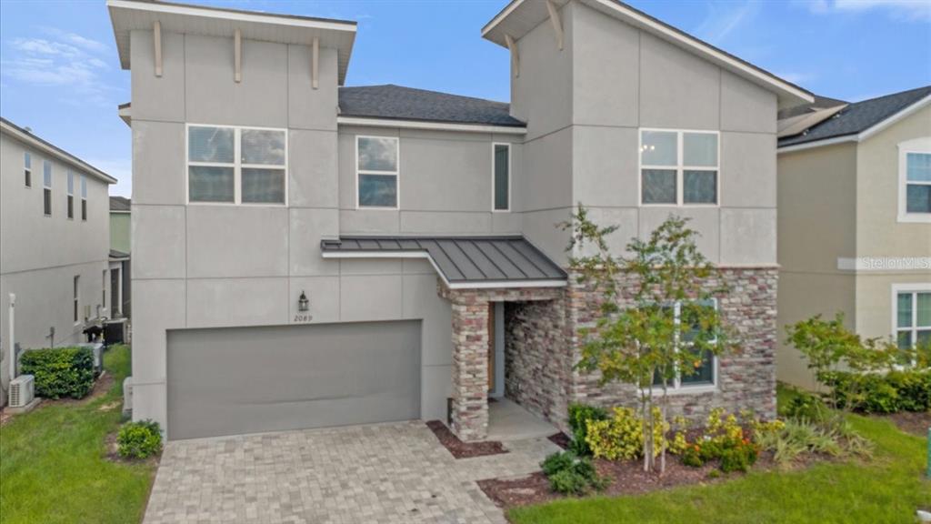 A two-story house with a gray facade, stone accents, and a two-car garage — 2089 TROPICAL PALMS CIRCLE, KISSIMMEE, FL
