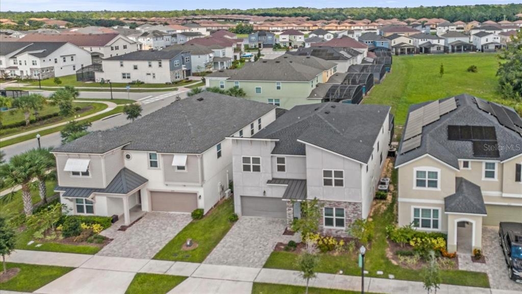 An aerial view shows three suburban houses with paved driveways and green lawns — 2089 TROPICAL PALMS CIRCLE, KISSIMMEE, FL