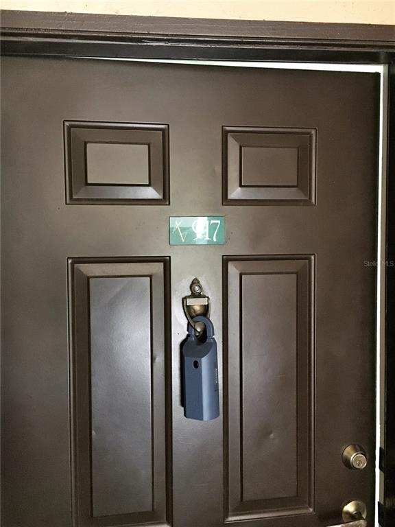 A dark brown door features a unit number plaque and a blue lockbox hanging below — 13917 FAIRWAY ISLAND DRIVE UNIT 917, ORLANDO, FL