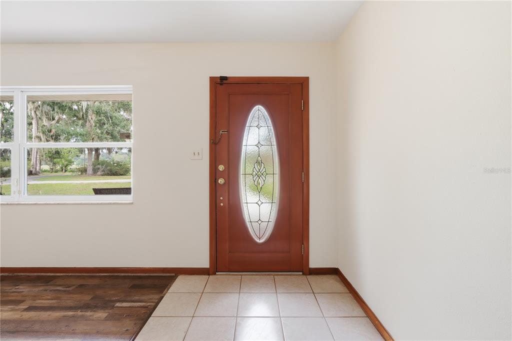 An entryway features a wood-framed door with an oval glass insert and tiled flooring — 5025 BASEBALL POND ROAD, BROOKSVILLE, FL