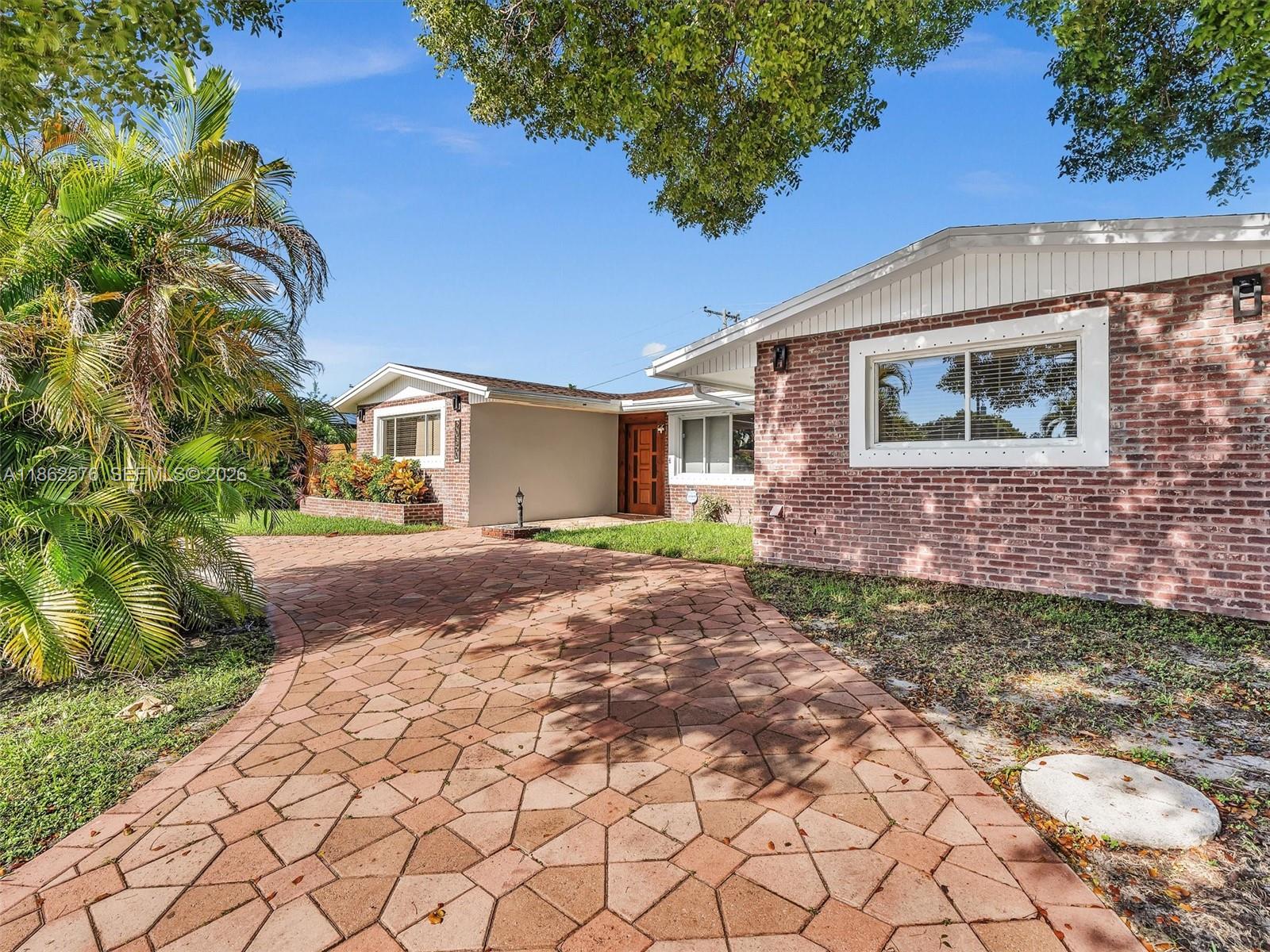 A brick house with a paved driveway and a palm tree in the front yard — 20350 Highland Lakes Blvd, Miami FL 33179, MIAMI, FL