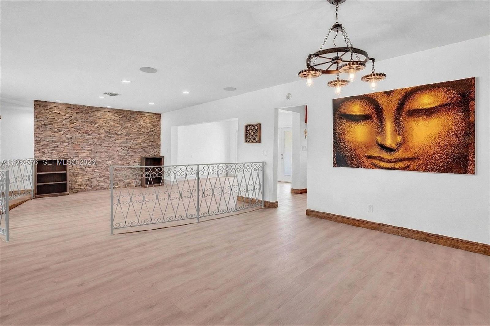 A living room features light wood flooring, a stone accent wall, and a decorative metal railing — 20350 Highland Lakes Blvd, Miami FL 33179, MIAMI, FL