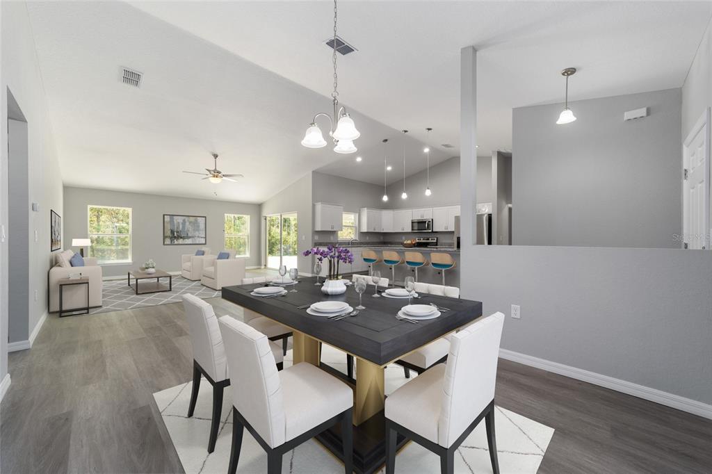 An open-concept dining area with a dark table and white chairs leads into a kitchen — 3617 SW BREEZY POINT DR, DUNNELLON, FL