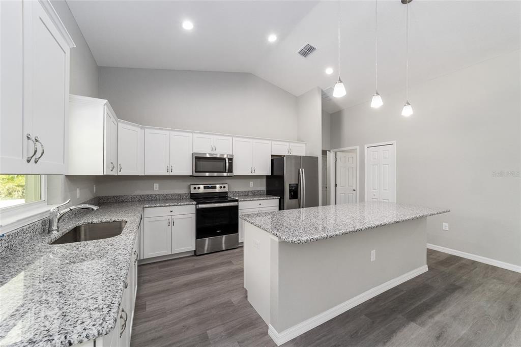 A kitchen with white cabinets, granite countertops, stainless steel appliances, and a central island — 3617 SW BREEZY POINT DR, DUNNELLON, FL