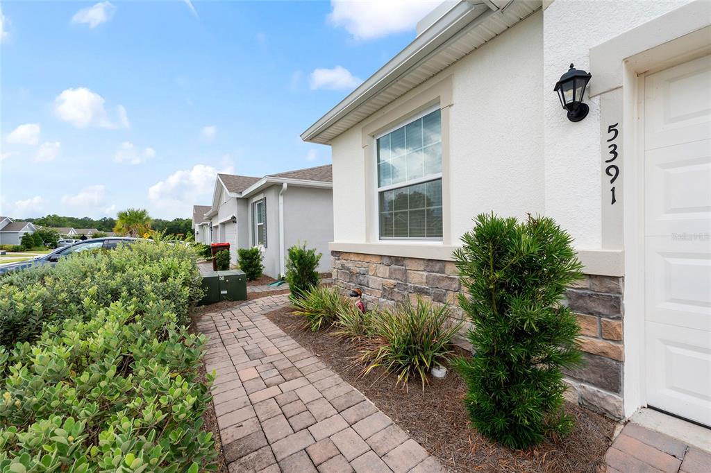 A paved walkway leads to the entrance of a house with stone veneer and siding — 5391 NW 46TH LANE ROAD, OCALA, FL