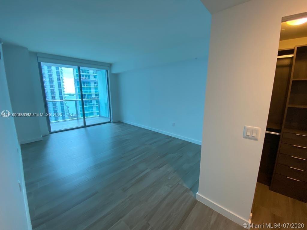 An empty bedroom features light wood flooring, a walk-in closet, and a balcony with water views — 1100 S MIAMI AVE # 3011, Miami FL 33130, MIAMI, FL
