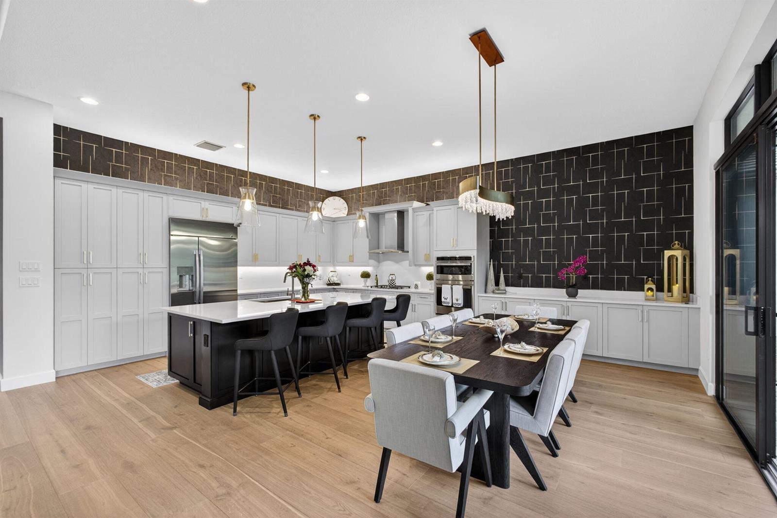 A modern kitchen and dining area features light gray cabinetry, a dark island, and patterned wallpaper — 11104 Glen Orchard Lane, Boynton Beach FL 33473, BOYNTON BEACH, FL