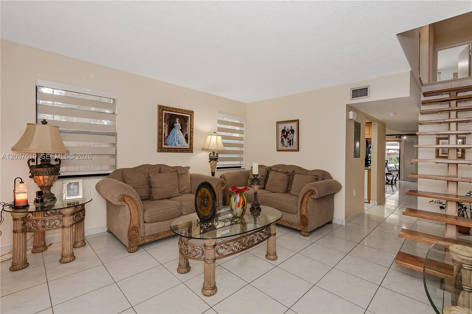 A living room features two beige sofas, a glass coffee table, and a wooden staircase — 1052 W 79th St # 11, Hialeah FL 33014, HIALEAH, FL