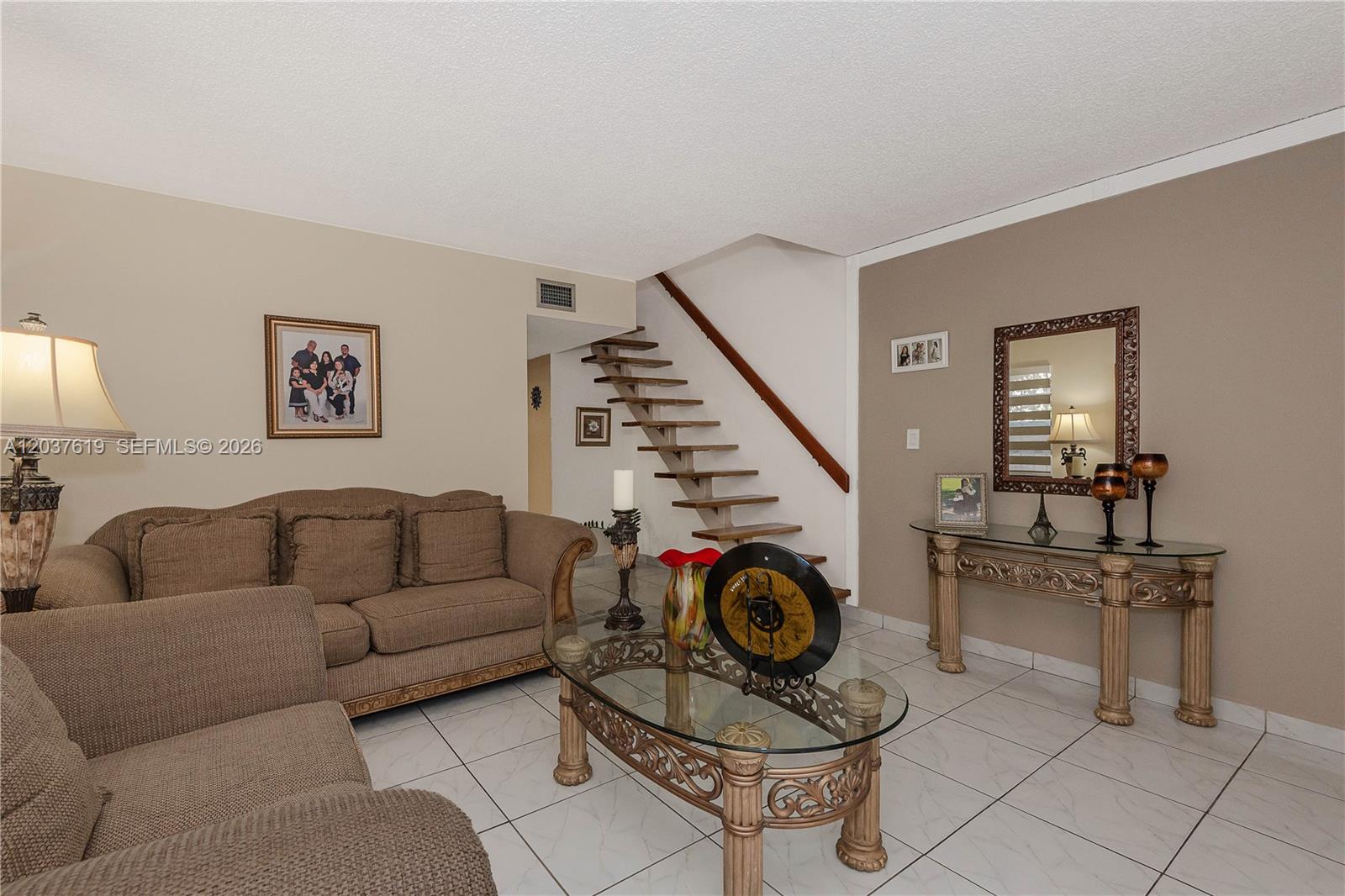 A living room features tile flooring, a brown sofa, a glass coffee table, and stairs — 1052 W 79th St # 11, Hialeah FL 33014, HIALEAH, FL