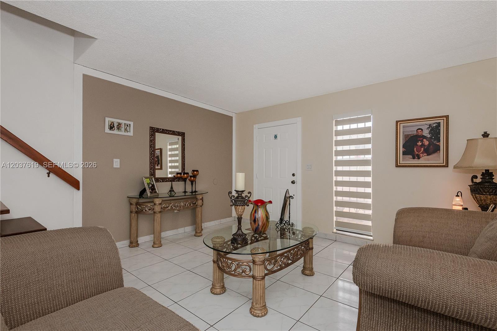 A living room features a glass coffee table, tiled floors, a console table, and stairs — 1052 W 79th St # 11, Hialeah FL 33014, HIALEAH, FL