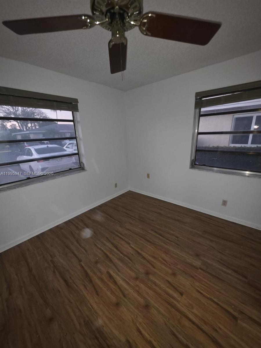 An empty bedroom features wood-look flooring, a ceiling fan, and two windows with blinds — 13731 Flora Pl # A, Delray Beach FL 33484, DELRAY BEACH, FL
