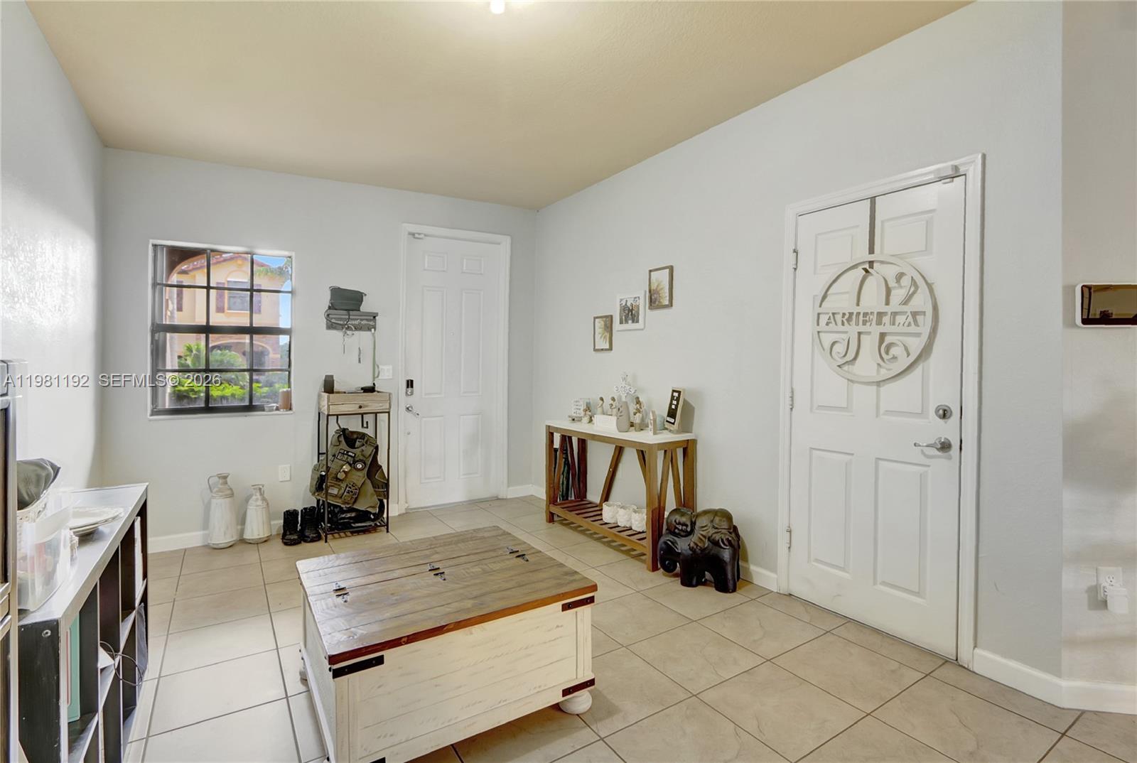 An entryway features tile flooring, a wooden coffee table, a console table, and two doors — 338 NE 37th Ave, Homestead FL 33033, HOMESTEAD, FL