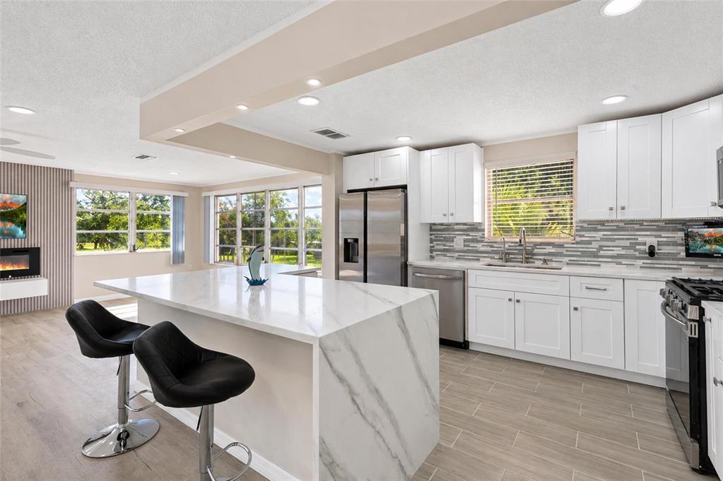 A modern kitchen features a marble-topped island, white cabinetry, and stainless steel appliances — 5623 80TH STREET N UNIT 316, ST PETERSBURG, FL