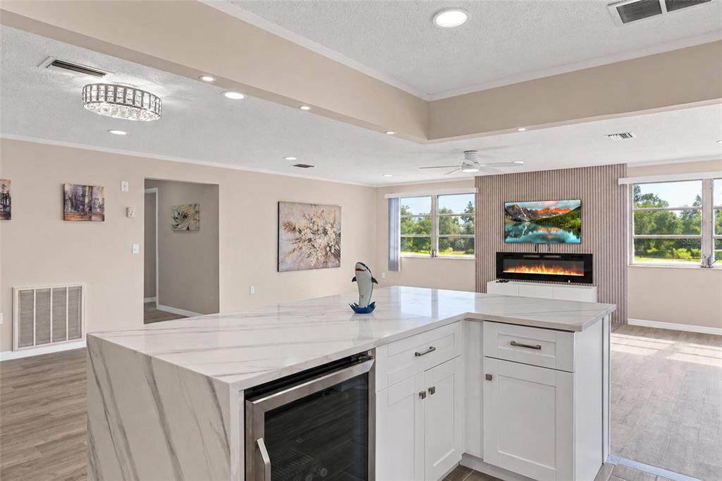 A kitchen island with a marble countertop and wine cooler sits in a bright living area — 5623 80TH STREET N UNIT 316, ST PETERSBURG, FL