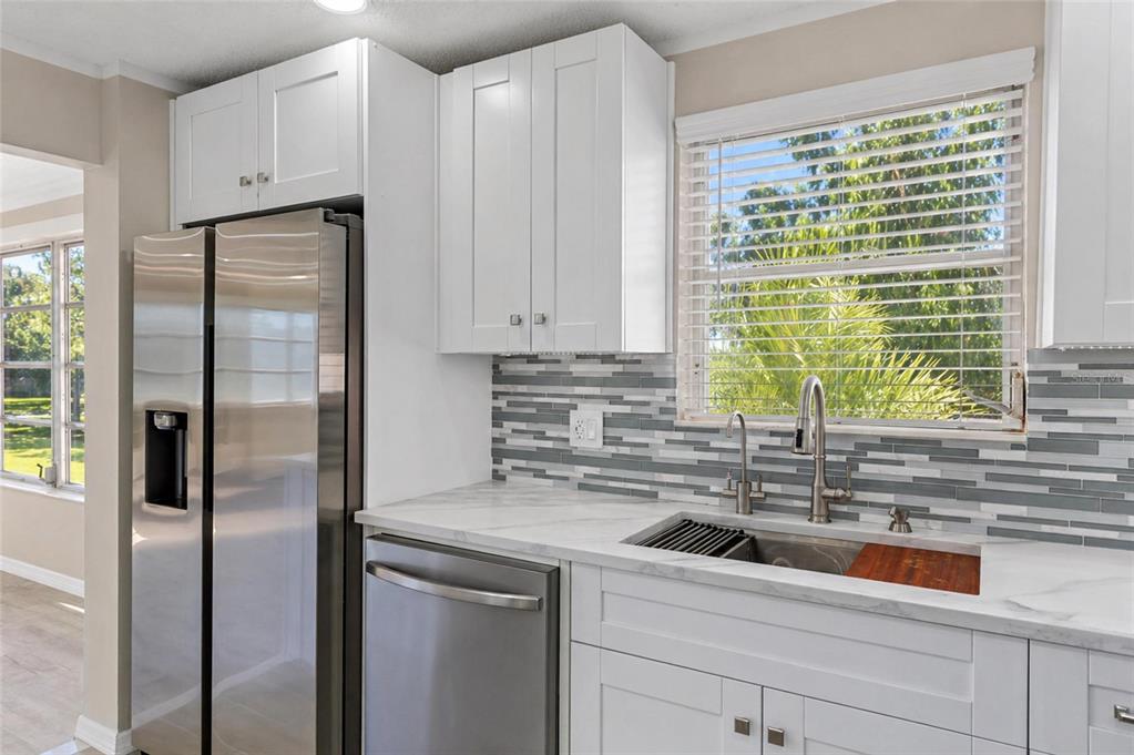 A kitchen features white cabinets, stainless steel appliances, a marble countertop, and a tiled backsplash — 5623 80TH STREET N UNIT 316, ST PETERSBURG, FL