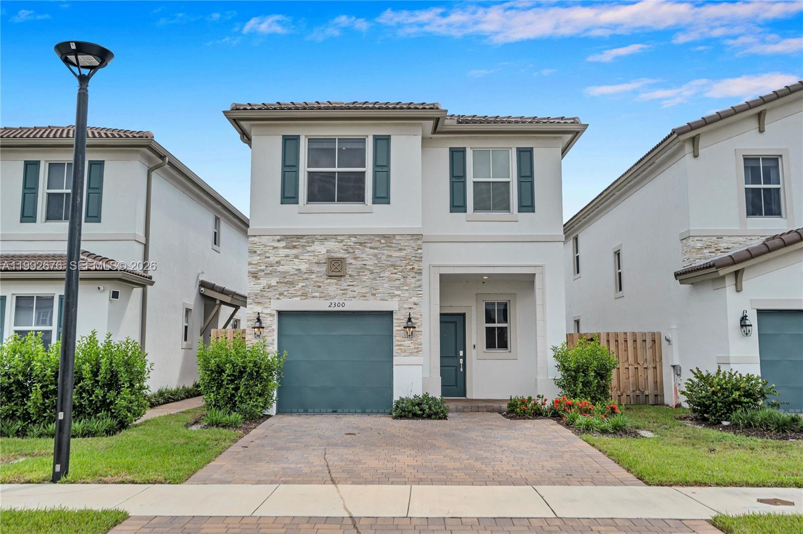 A two-story house with a stone facade, teal garage door, and a paved driveway — 2300 NW 130th St, Miami FL 33167, MIAMI, FL