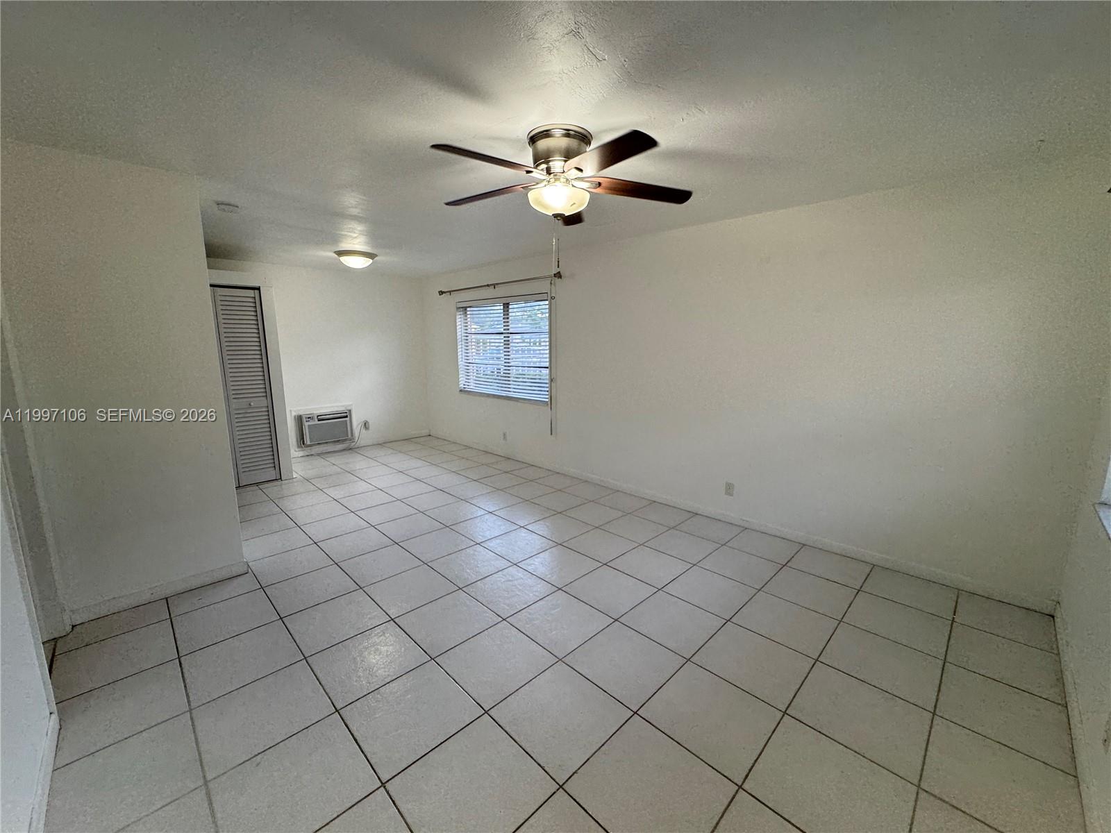 An empty room features white walls, light-colored tile flooring, a ceiling fan, and a window — 2000 Buchanan St # 11, Hollywood FL 33020, HOLLYWOOD, FL