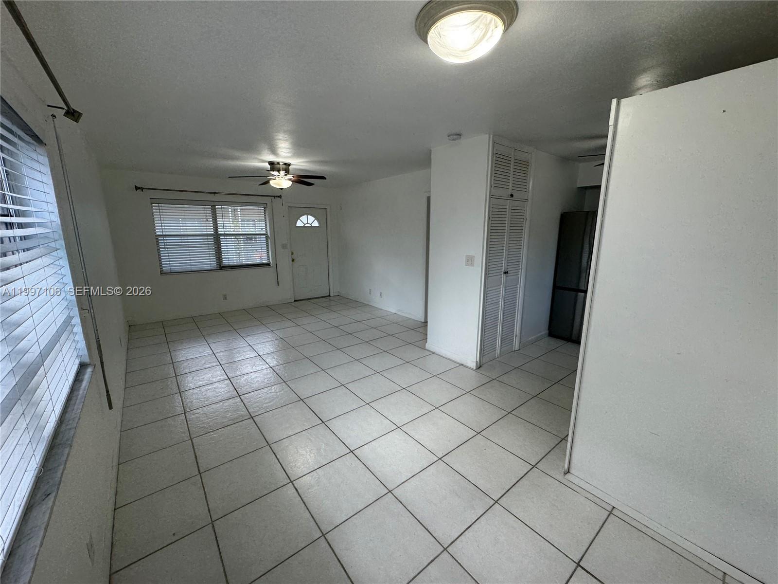 A bright, open-concept living area features white tile flooring, white walls, and a ceiling fan — 2000 Buchanan St # 11, Hollywood FL 33020, HOLLYWOOD, FL