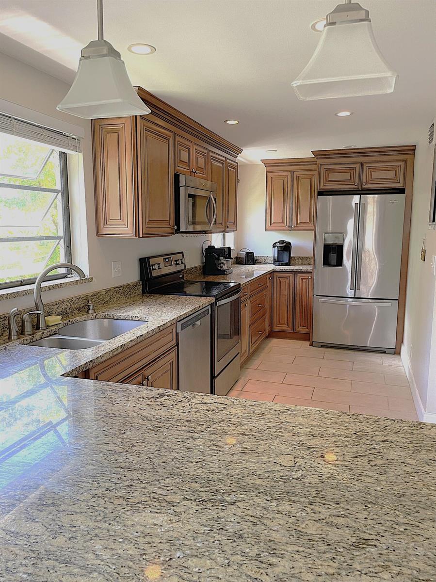 A kitchen with wood cabinets, granite countertops, stainless steel appliances, and tile flooring — 367 S Federal Highway # C426, Deerfield Beach FL 33441, DEERFIELD BEACH, FL