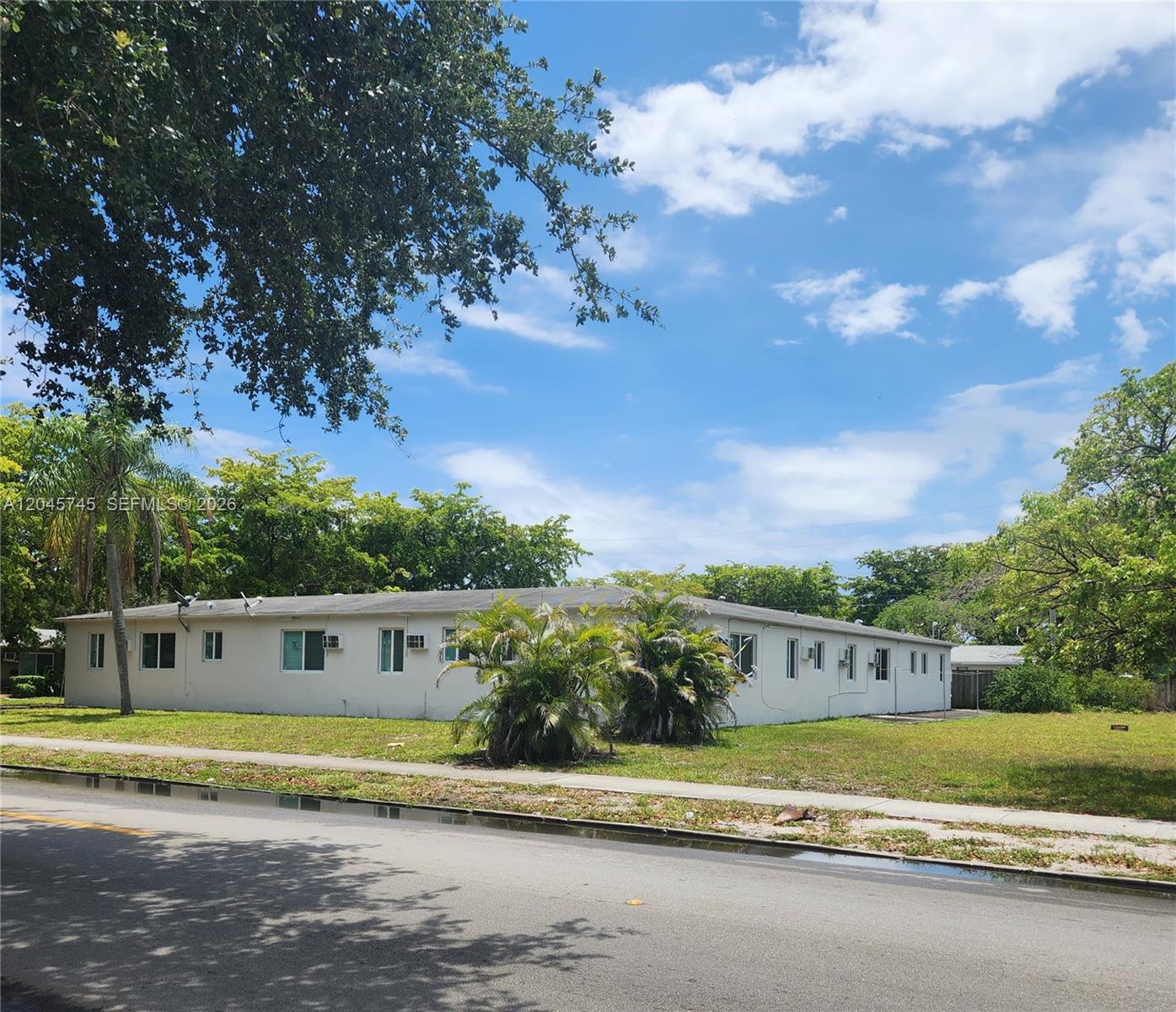 A low-rise, light-colored apartment building sits on a grassy lot next to a street — 2000 Washington St, Hollywood FL 33020, HOLLYWOOD, FL