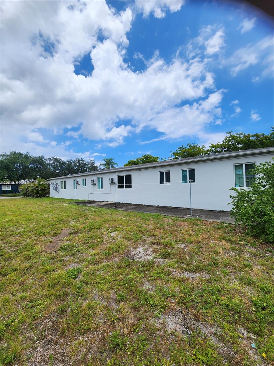 A long, single-story white building with multiple windows sits beside a grassy yard — 2000 Washington St, Hollywood FL 33020, HOLLYWOOD, FL