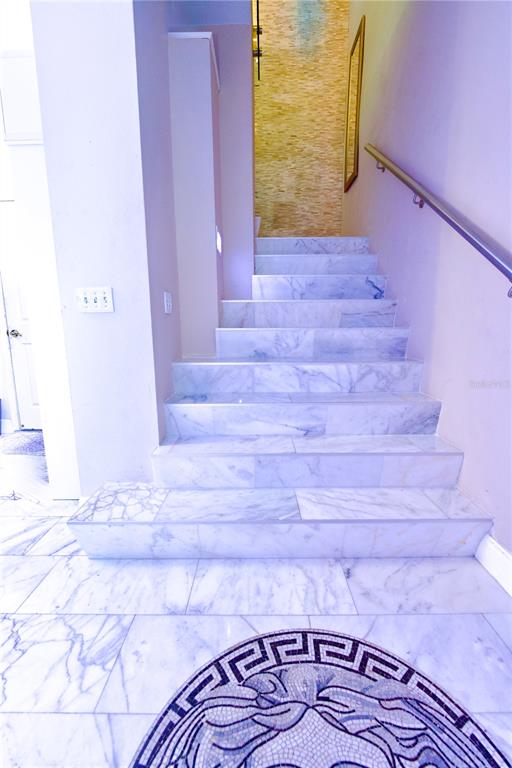 A marble staircase leads upward in a foyer featuring a decorative circular floor mosaic — 1437 HARBOUR WALK ROAD, TAMPA, FL