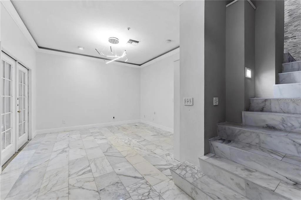 A room with white marble flooring, a modern light fixture, and a marble staircase — 1437 HARBOUR WALK ROAD, TAMPA, FL