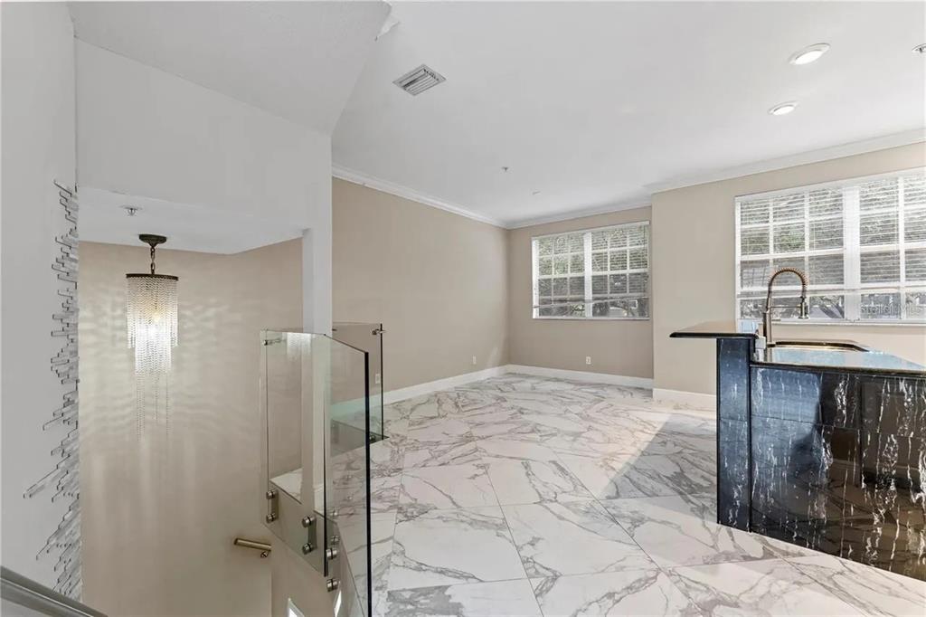 A room with marble-patterned tile flooring, a glass stair railing, and a black marble counter — 1437 HARBOUR WALK ROAD, TAMPA, FL