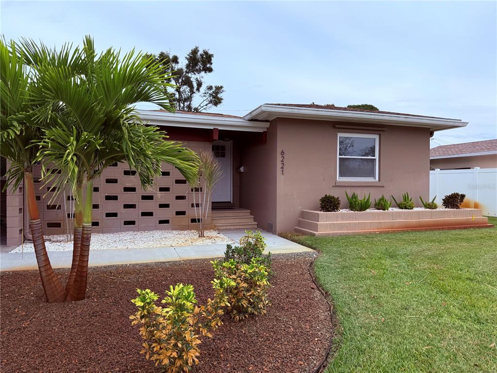 A single-story house with a brown stucco exterior, a decorative block wall, and a palm tree — 6221 6TH AVENUE N, ST PETERSBURG, FL