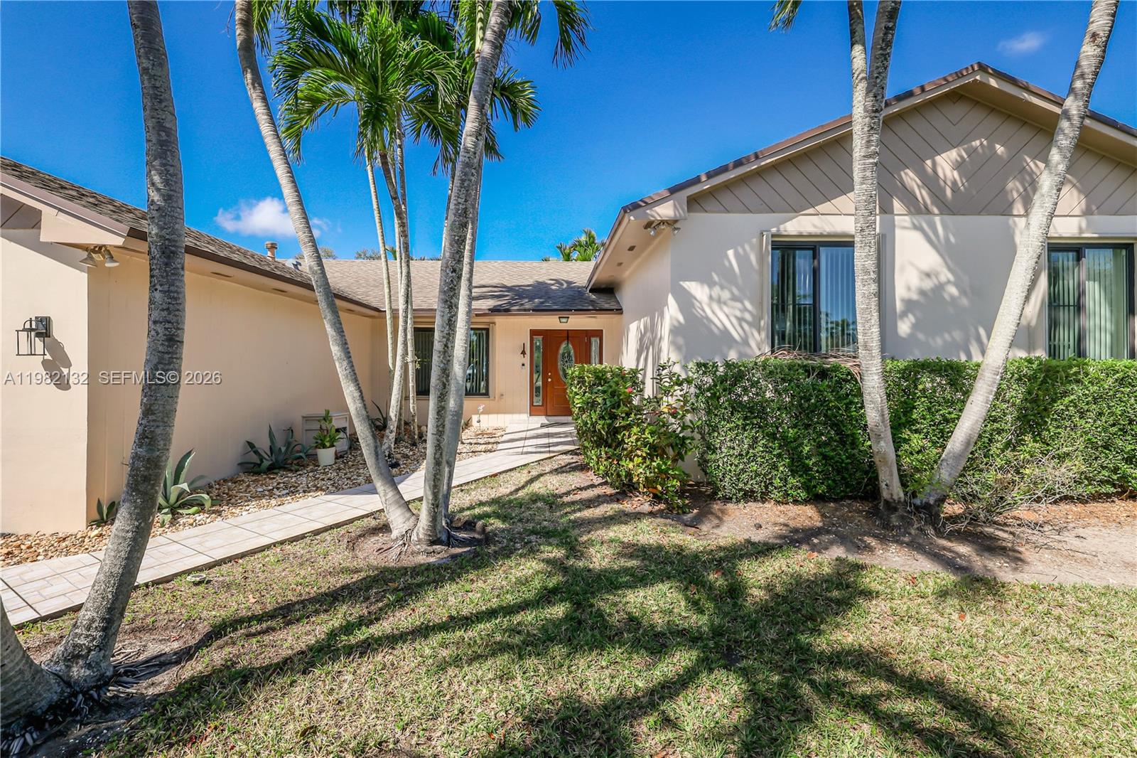 A tan house exterior features a paved walkway leading to a wooden front door — 11541 SW 100th St, Miami FL 33176, MIAMI, FL