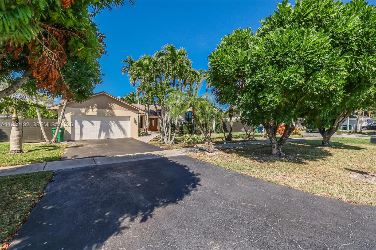 A single-story house with a two-car garage, driveway, and palm trees under a blue sky — 11541 SW 100th St, Miami FL 33176, MIAMI, FL