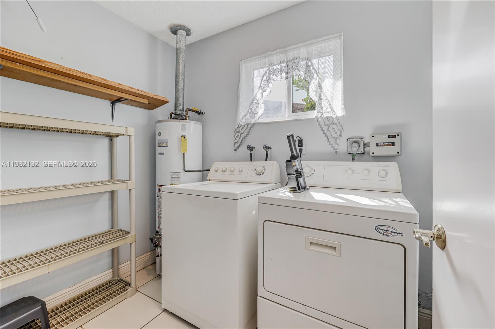 A laundry room features a washer, dryer, water heater, and shelving against light-colored walls — 11541 SW 100th St, Miami FL 33176, MIAMI, FL