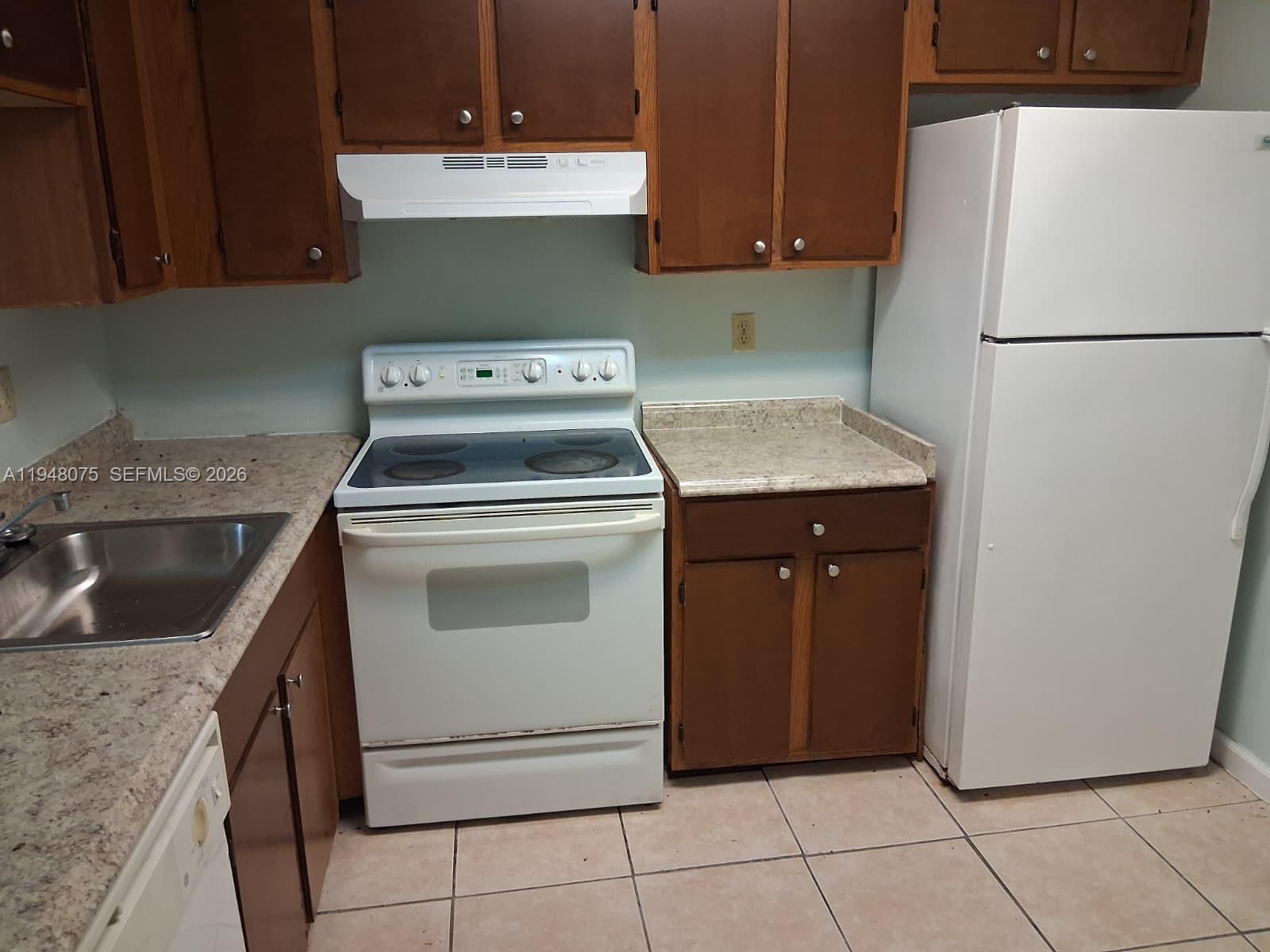 A kitchen features brown wooden cabinets, a white stove, a white refrigerator, and laminate countertops — 19791 SW 114th Ave # 135, Miami FL 33157, MIAMI, FL