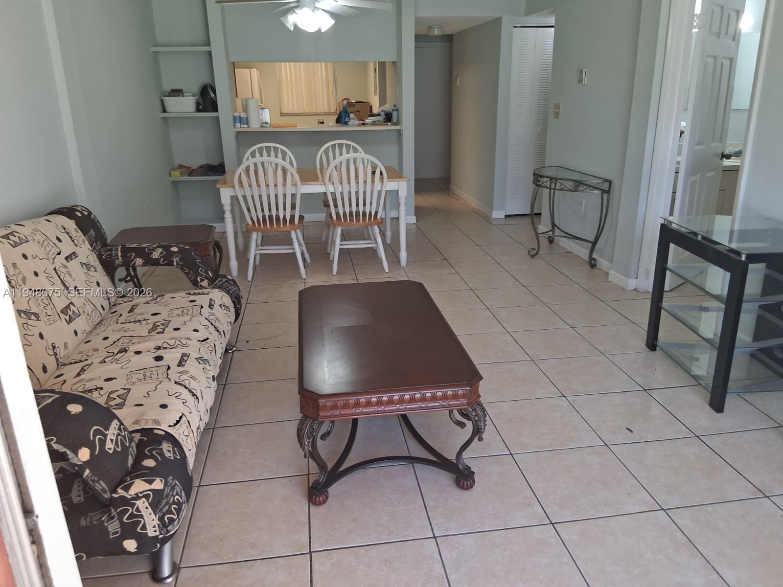 A living and dining area features tiled floors, a patterned sofa, and a coffee table — 19791 SW 114th Ave # 135, Miami FL 33157, MIAMI, FL