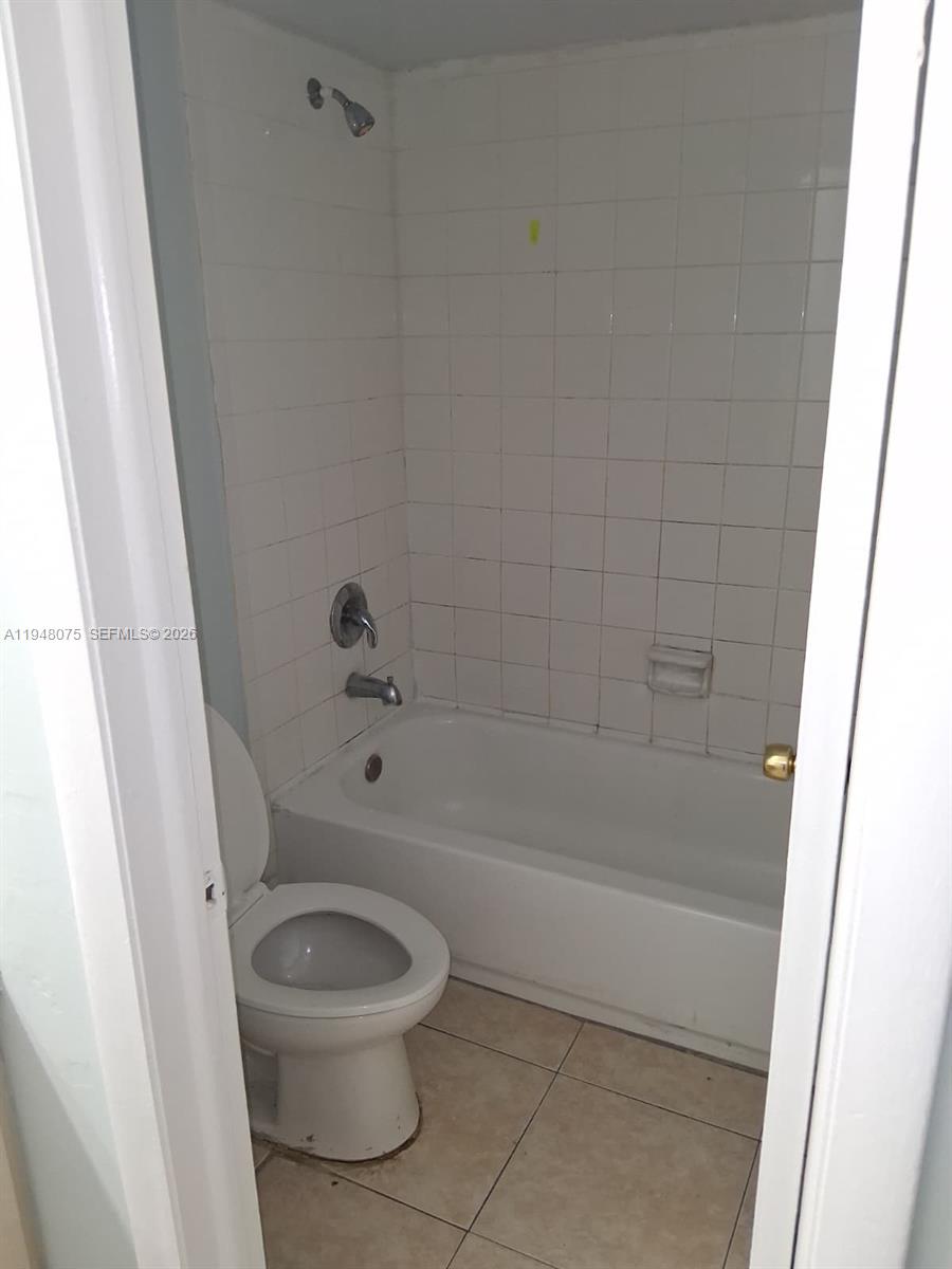 A small bathroom features a white toilet, a bathtub with a showerhead, and tiled walls — 19791 SW 114th Ave # 135, Miami FL 33157, MIAMI, FL
