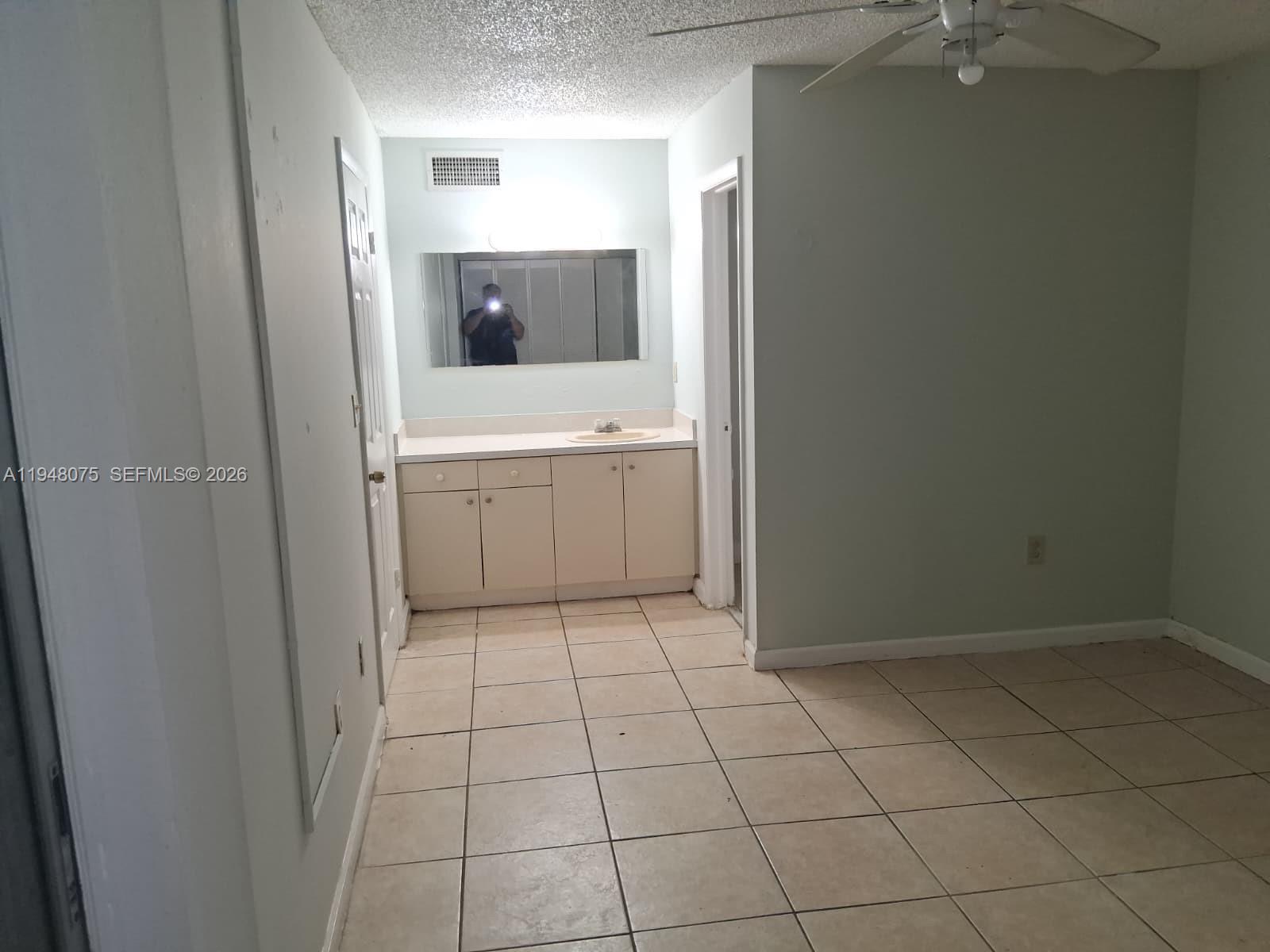 A bathroom vanity with a mirror and tile flooring sits in an open room — 19791 SW 114th Ave # 135, Miami FL 33157, MIAMI, FL