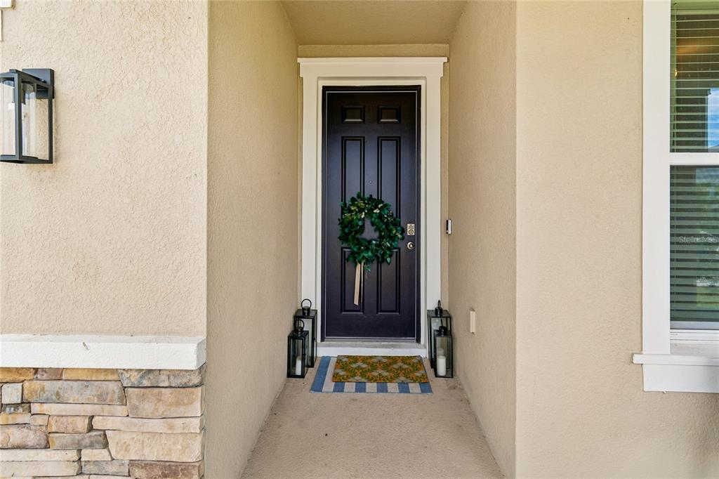A dark front door with a wreath sits in a recessed entryway with stone accents — 2510 WARREN ACRES BOULEVARD, WESLEY CHAPEL, FL
