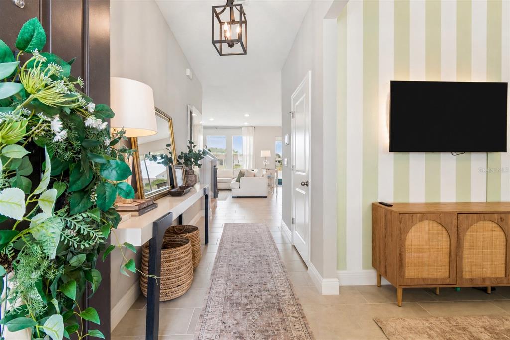 A hallway with a console table, striped accent wall, and a view into the living room — 2510 WARREN ACRES BOULEVARD, WESLEY CHAPEL, FL
