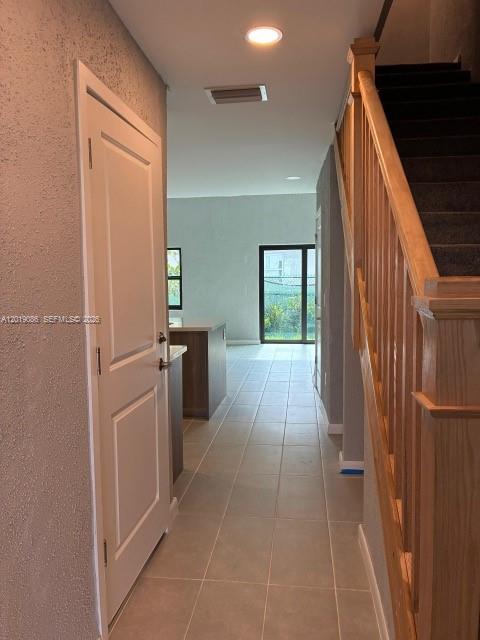A hallway with tile flooring leads toward a kitchen and a sliding glass door — 2511 Pierce St # 6, Hollywood FL 33020, HOLLYWOOD, FL