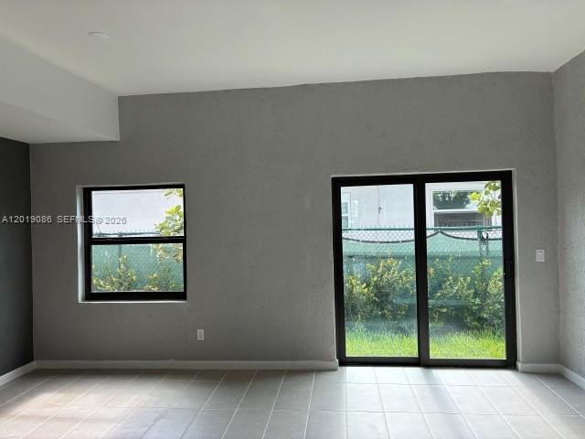 A room with light-colored tile flooring, gray walls, a window, and sliding glass doors — 2511 Pierce St # 6, Hollywood FL 33020, HOLLYWOOD, FL
